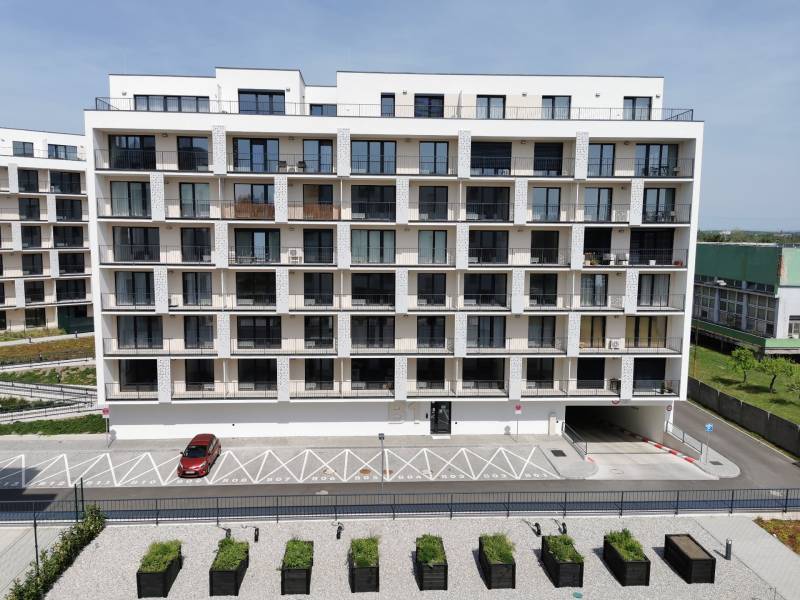 A modern apartment building with parking spaces and greenery on Eduarda Wenzla Street in Bratislava - Rača.