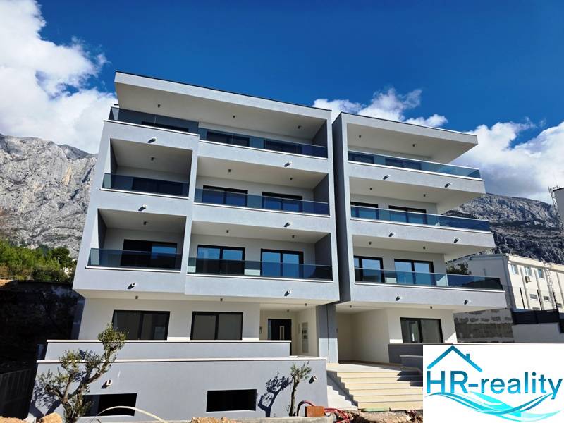 A recreational apartment in Makarska, a building with four floors and balconies, mountain backdrop.