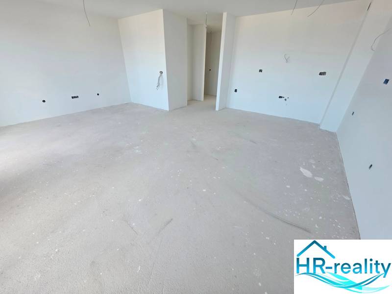 Spacious unfinished room in a Recreational Apartment with white walls and concrete floor.