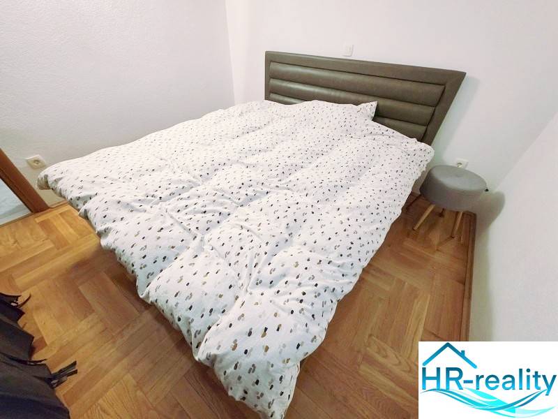 Recreational apartment with a bed, wooden floor decor, and a small nightstand.