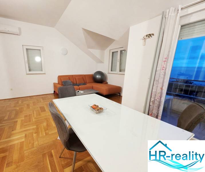 Dining room and living room in a holiday apartment with wood-patterned flooring.