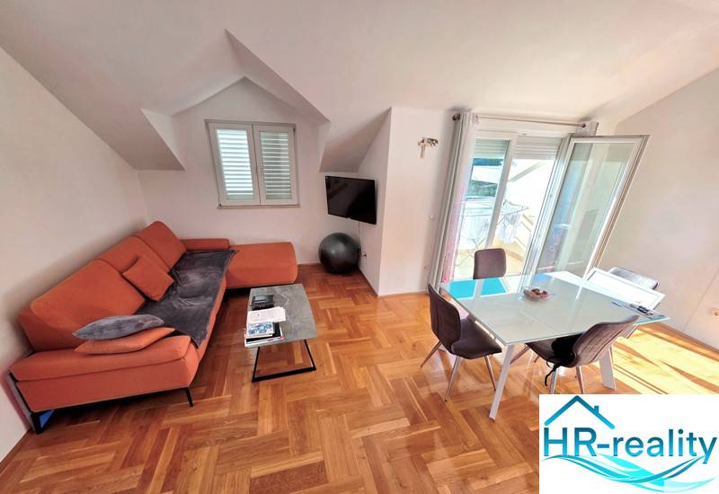 The recreational apartment offers a sofa, a dining table, and a floor with a wooden decor.
