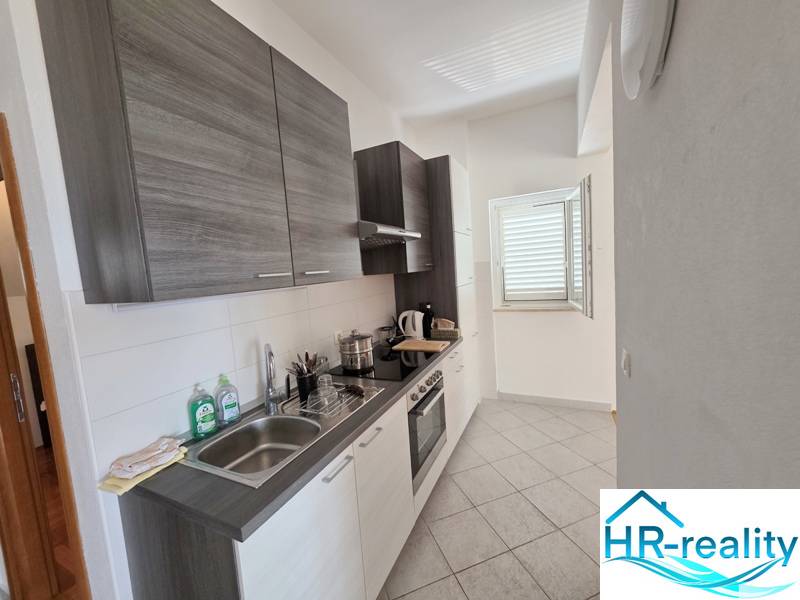 The kitchen of a holiday apartment with modern equipment and a window that illuminates the space.