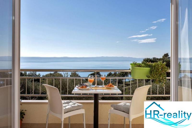 The balcony of a 3-room apartment in Makarska with a sea view and a table with drinks.