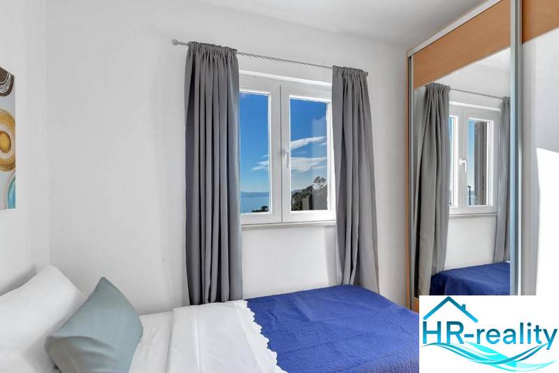 A bedroom in a 3-room apartment with a view of the sea through the window.