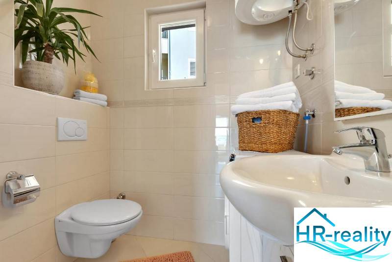 A bathroom in a 3-room apartment with a toilet, sink, and tasteful accessories.