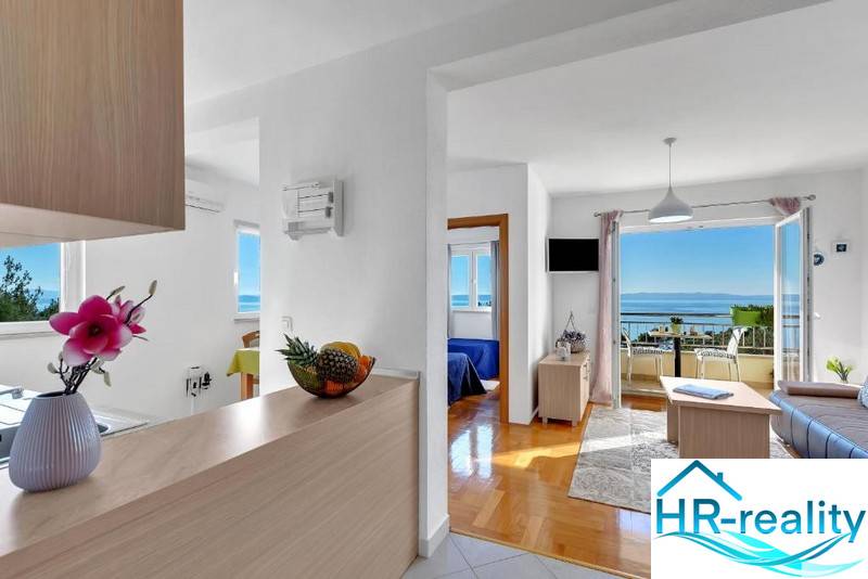 A bright living room with wood-patterned flooring and a sea view in a 3-room apartment.