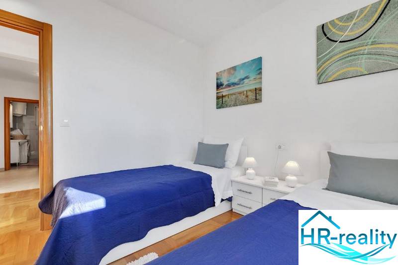 Bedroom in a 3-room apartment with two beds, white furniture, and a wooden decor floor.