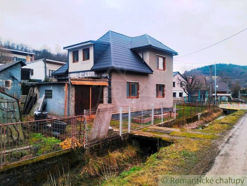 A family house in Jasenica with a sloped roof, fence, and adjacent road.