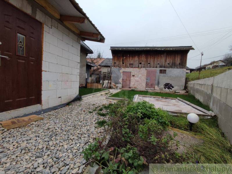 A family house in Jasenica with a yard, a gravel path, and a wooden garage.