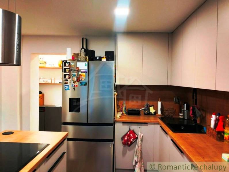 A kitchen in a family house with a stainless steel refrigerator and wooden countertops.