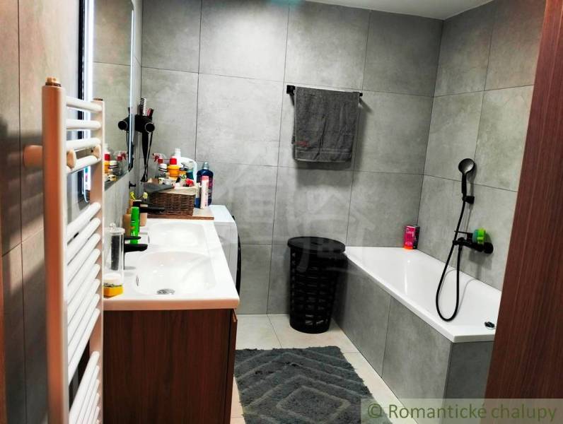 Bathroom with a bathtub, double sink, mirror, and bathroom radiator in a family house.