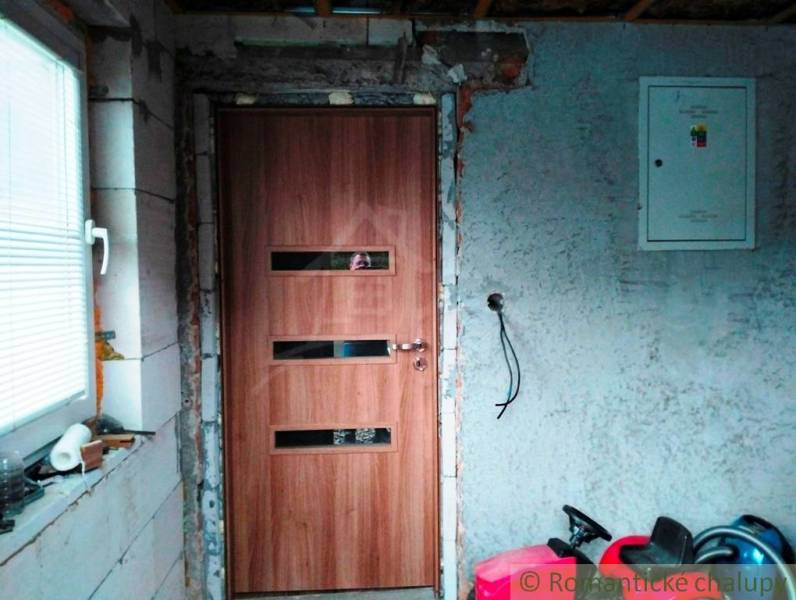 The interior of a family house with doors featuring a wood decor and an unfinished wall.