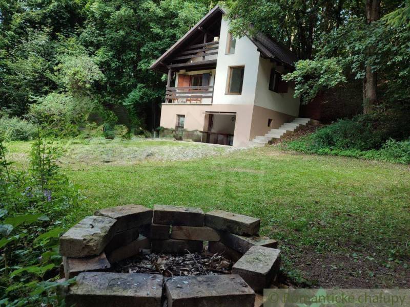 A family house in Mojtín with a fire pit and a grassy garden surrounded by trees.
