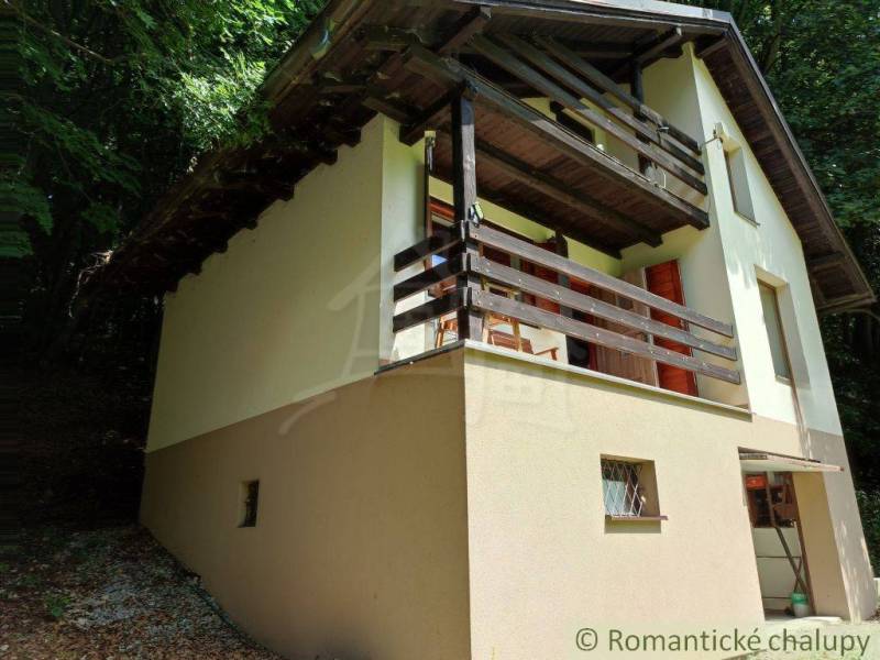 A family house in Mojtín with a wooden balcony surrounded by greenery and trees.