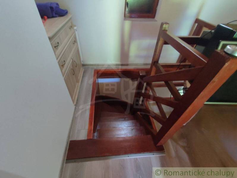 A staircase with a wooden railing in a family house, next to it are drawer cabinets.