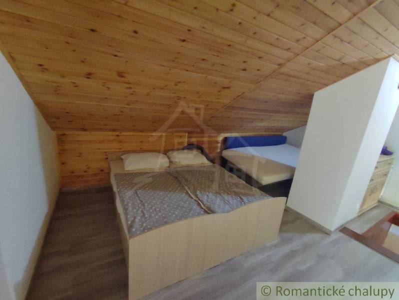 Attic bedroom in a family house with two beds and a wooden decor floor.