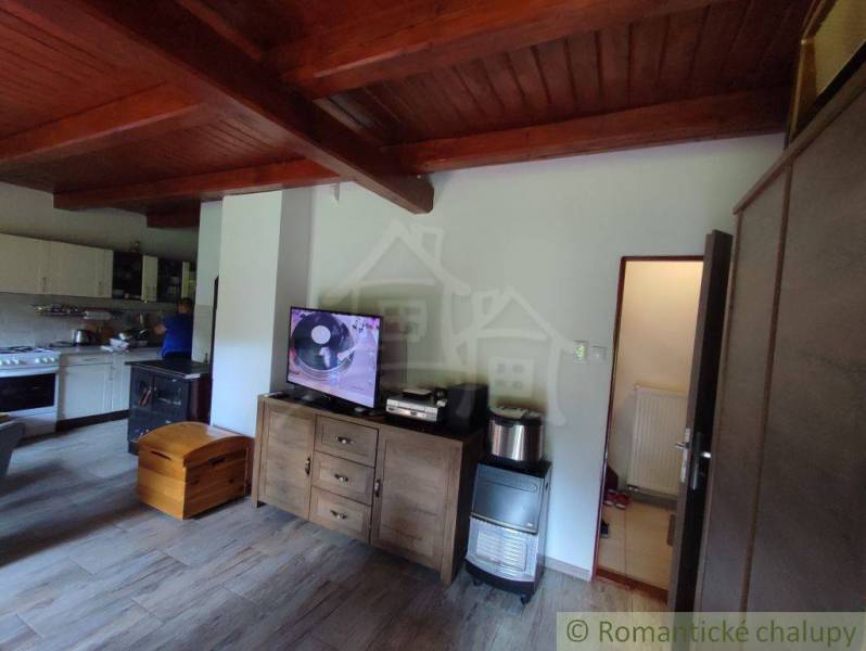 Interior of a family house with a wooden decor floor, television, and kitchen unit.