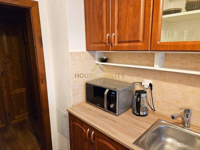 A kitchen unit with a sink, microwave, and kettle in a 3-room apartment.