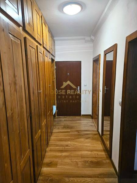 A hallway in a 3-room apartment with a wooden decor floor and built-in wardrobes.