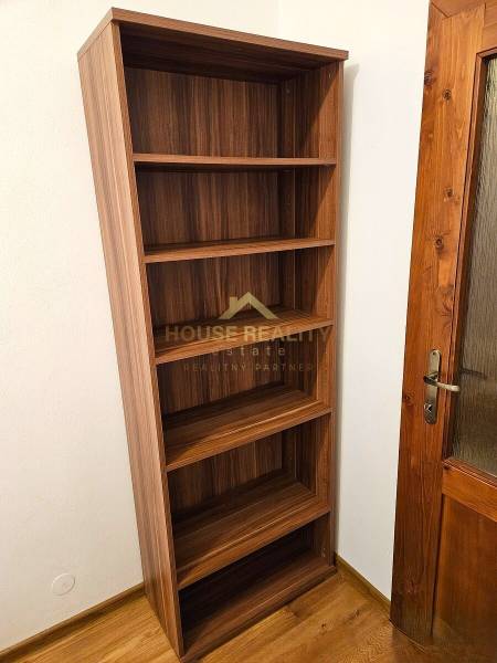 A shelf with five shelves next to wooden doors and a floor with a wooden decor.