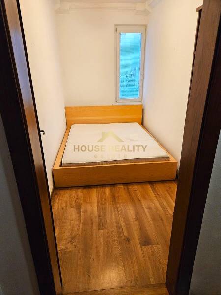 A bedroom in a 3-room apartment with a bed and a wooden decor floor.