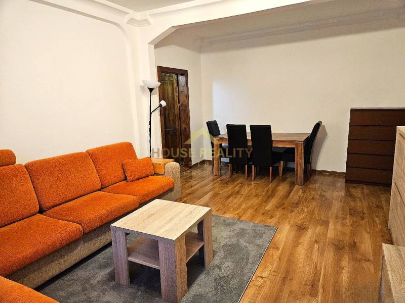 3-room apartment with an orange sofa, wooden table, and wooden decor flooring.