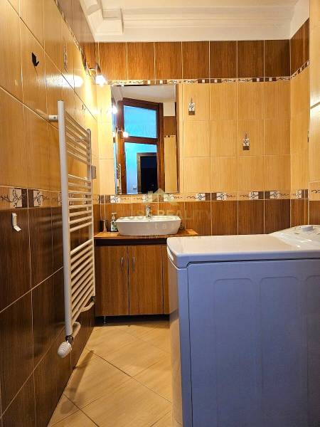 A bathroom in a 3-room apartment with light tiles, a sink, and a washing machine.