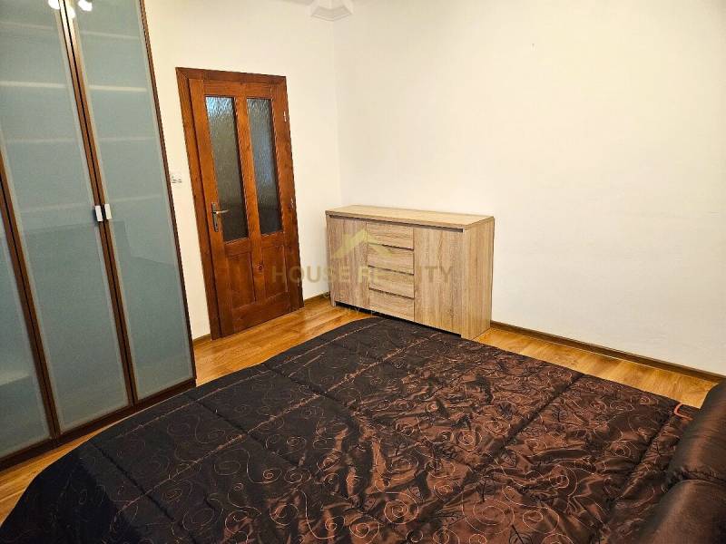 Bedroom in a 3-room apartment with a wooden decor floor, wardrobe, and dresser.