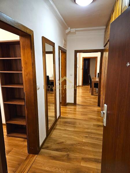 A hallway with a wooden decor floor in a 3-room apartment, built-in wardrobes and a mirror.
