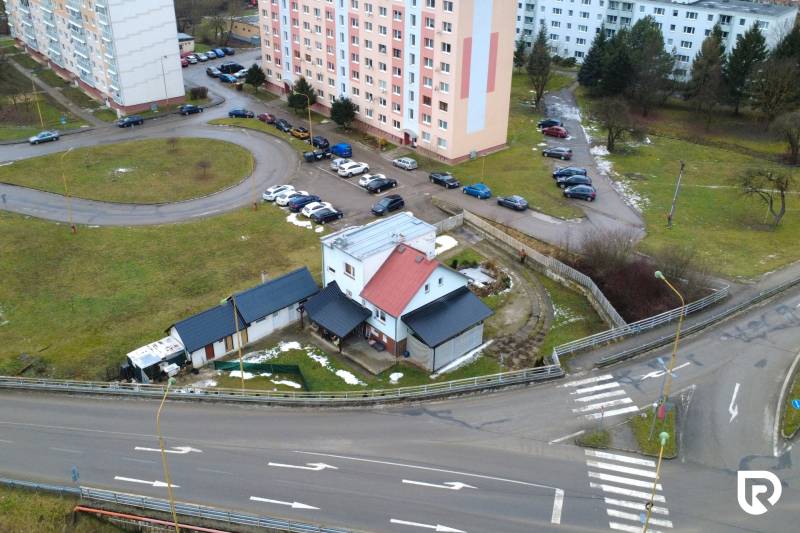 A family house on SNP Street in Považská Bystrica, surrounded by apartment buildings and a parking lot.