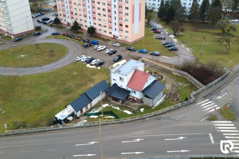 A family house in Považská Bystrica on SNP Street surrounded by a parking lot and apartment buildings.