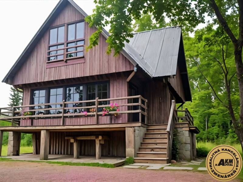 A wooden cottage in Kováčová surrounded by greenery with blooming flowers on the terrace.