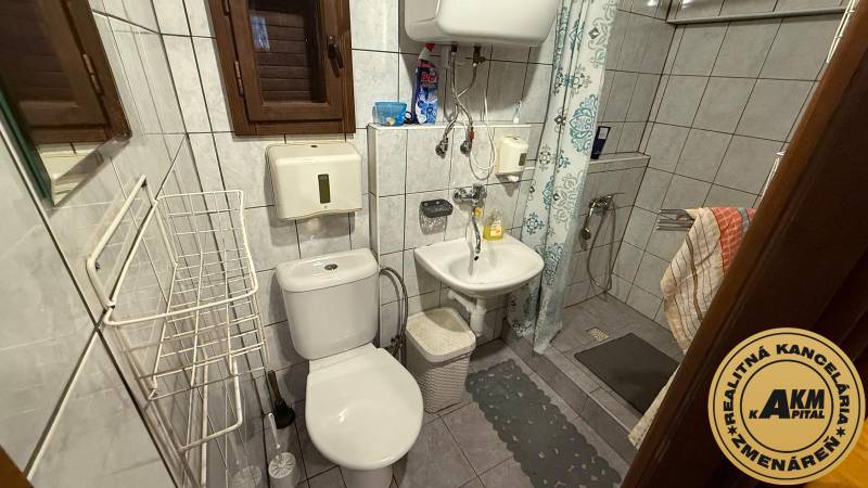 A bathroom in a cabin with a shower, sink, toilet, and tiled walls.