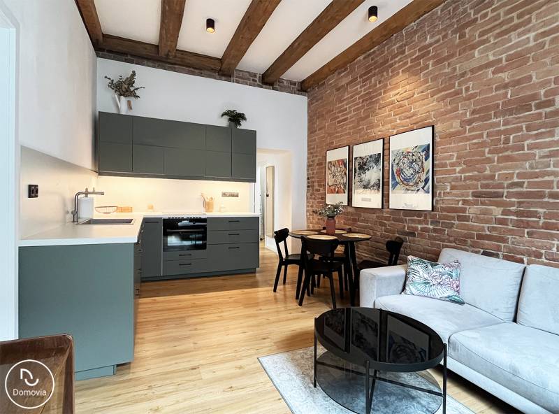 In a 2-room apartment on Vajnorská with a brick wall and modern beams, there is a cozy interior.