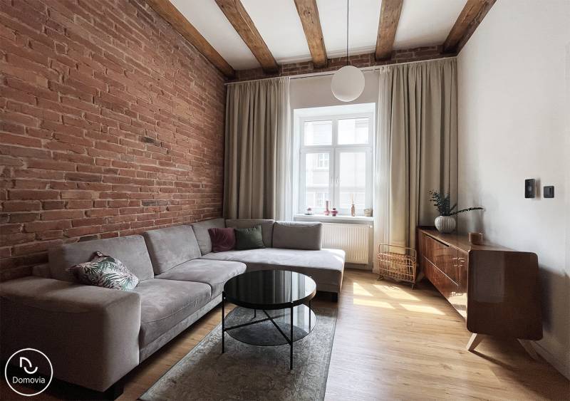 The living room in the 2-room apartment with a brick wall, Vajnorská, Bratislava, offers a comfortable sofa and a coffee table.