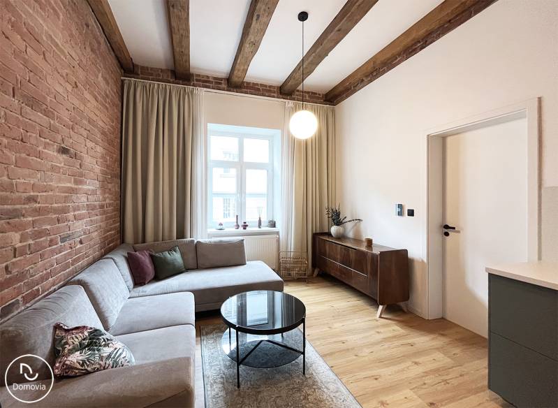 Bright living room with a brick wall and a sofa, on Vajnorská street in a 2-room apartment.