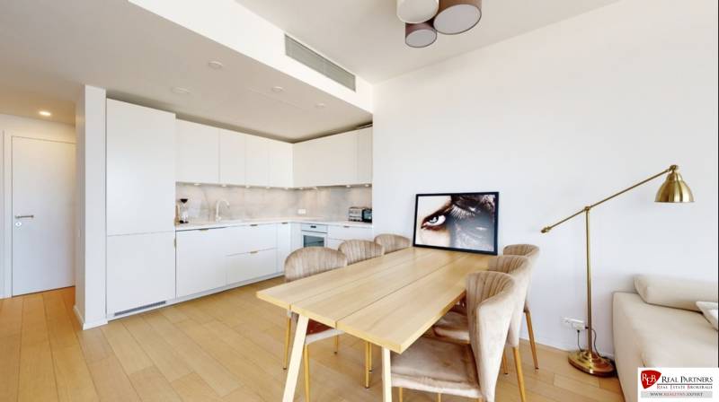 A kitchen in a 3-room apartment with a wooden decor floor, a dining table, and a lamp.