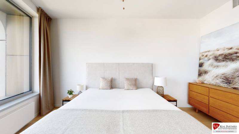 A room in a 3-room apartment with a large bed, a dresser, and a decorative painting.