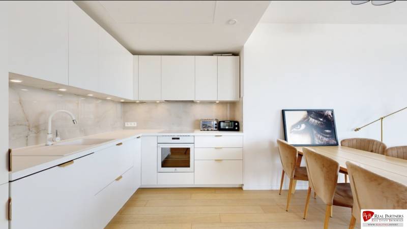 A kitchen in a 3-room apartment with white cabinets, floor with wood decor.