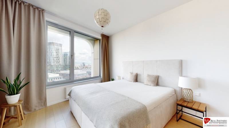Bedroom in a 3-room apartment with a large window, curtains, and a floor with a wooden decor.