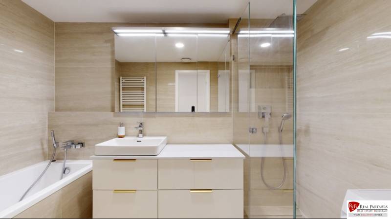 A stylish bathroom in a 3-room apartment with a bathtub, shower, and storage space.