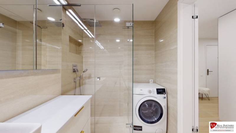 A bathroom with a shower and a washing machine in a 3-room apartment.