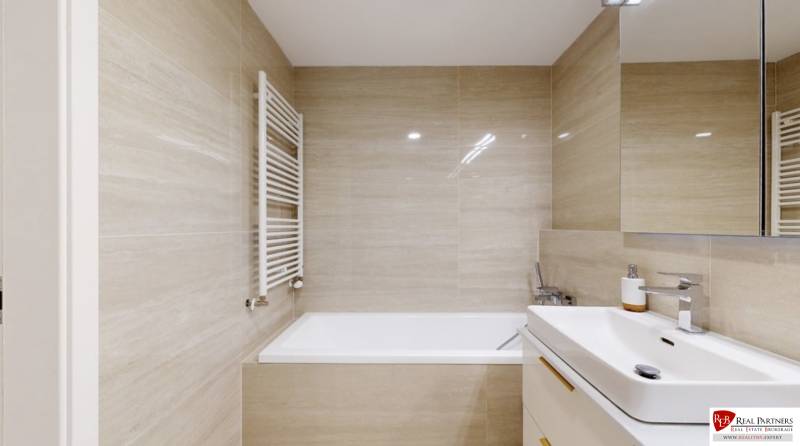 Bathroom with a bathtub, sink, and mirror in a 3-room apartment.