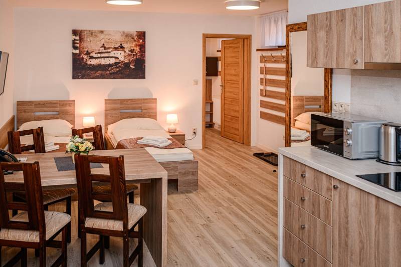 Interior of hotels and guesthouses with beds, kitchen units, and flooring with wood decor.