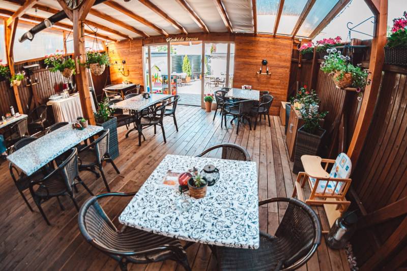 In hotels and guesthouses with wooden decor flooring, there are tables, chairs, and flowers.