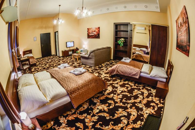A hotel room with a carpet, bed, sofa, and television. Hotels and guesthouses.