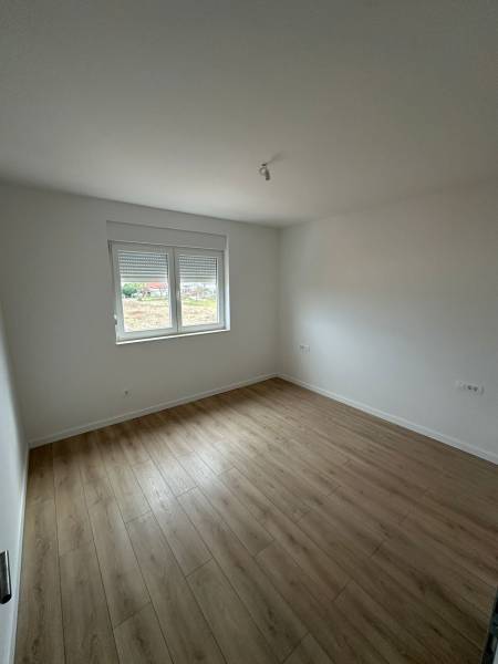A room in a 3-room apartment with a wooden decor floor and white walls.