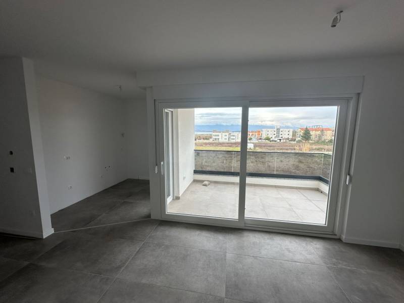 An empty room with large windows in a 3-room apartment, overlooking the balcony.