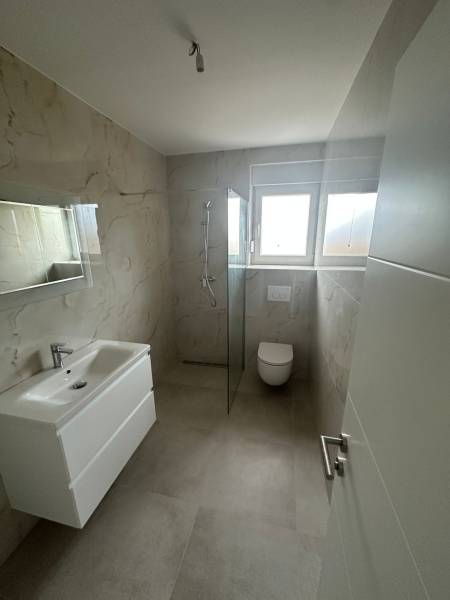 Bathroom in a 3-room apartment with a shower, sink, and toilet. Wall tiles with decor.